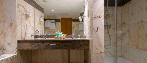 A modern bathroom with a marble vanity, a glass shower enclosure, and a wooden door.
