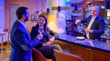 Eine Bar mit einem Barkeeper, einem sitzenden Gast und einem stehenden Gast.