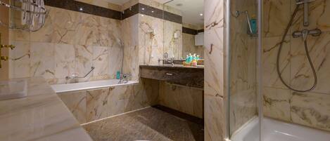 A bathroom with a bathtub, shower, toilet, and marble walls.
