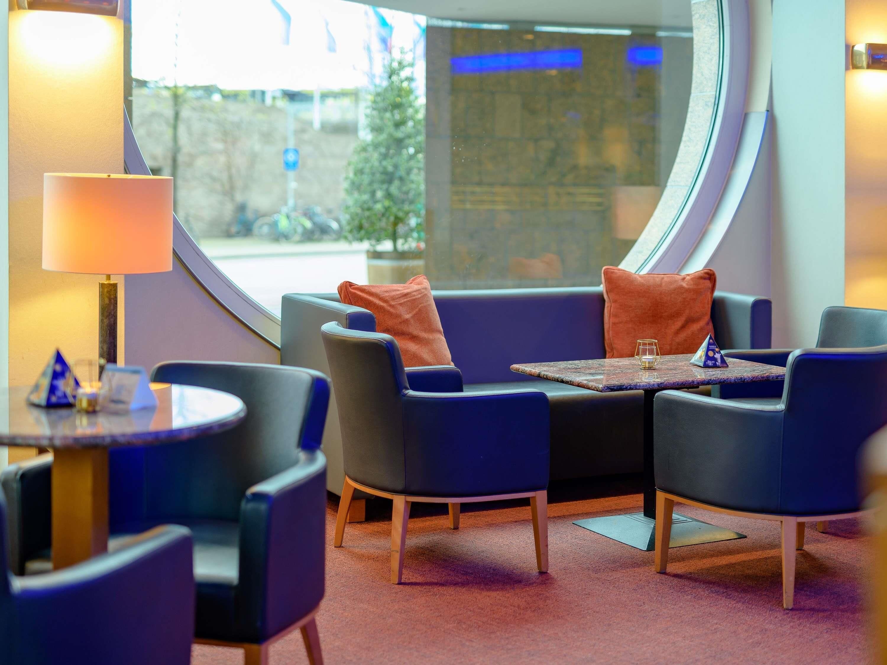 Een moderne zithoek met een ronde tafel, comfortabele stoelen en een lamp.