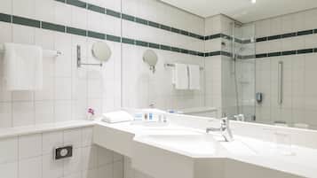 Ein modernes Badezimmer mit einem großen Waschbecken, zwei Spiegeln und einer Duschkabine aus Glas.