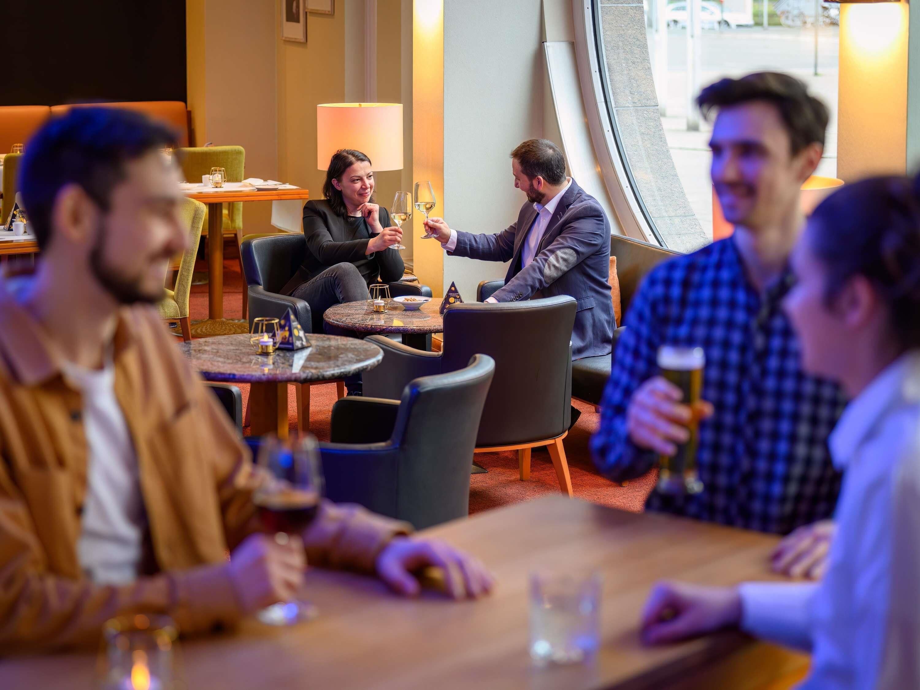 A group of people seated at a table in a modern indoor setting with round tables and comfortable seating.