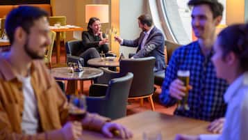 A group of people seated at a table in a modern indoor setting with round tables and comfortable seating.