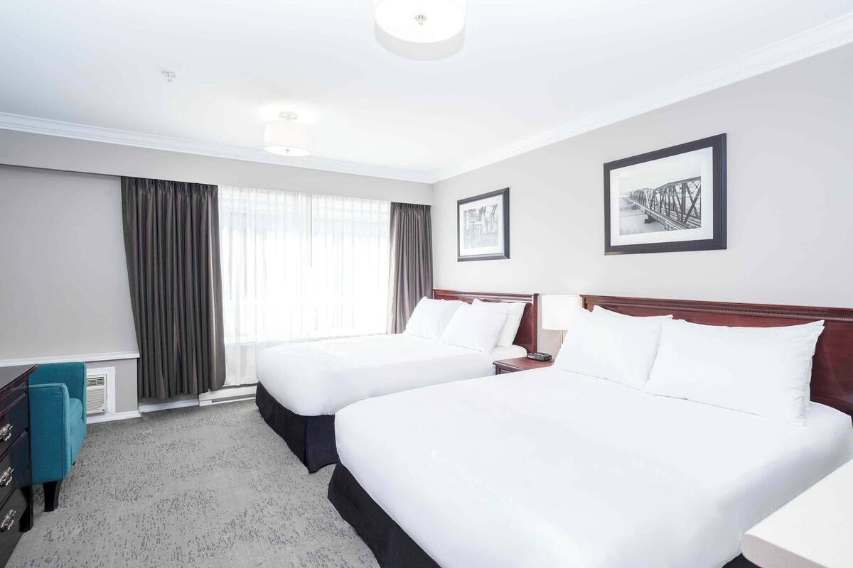 A hotel room with two beds, a desk, and a chair.