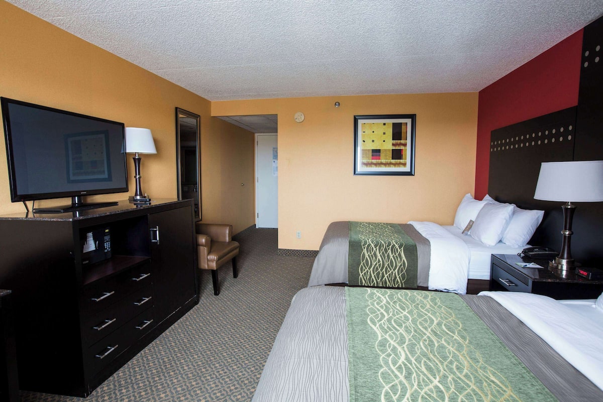 Une chambre d’hôtel comprenant un lit, un bureau avec un ordinateur, une télévision et une chaise.