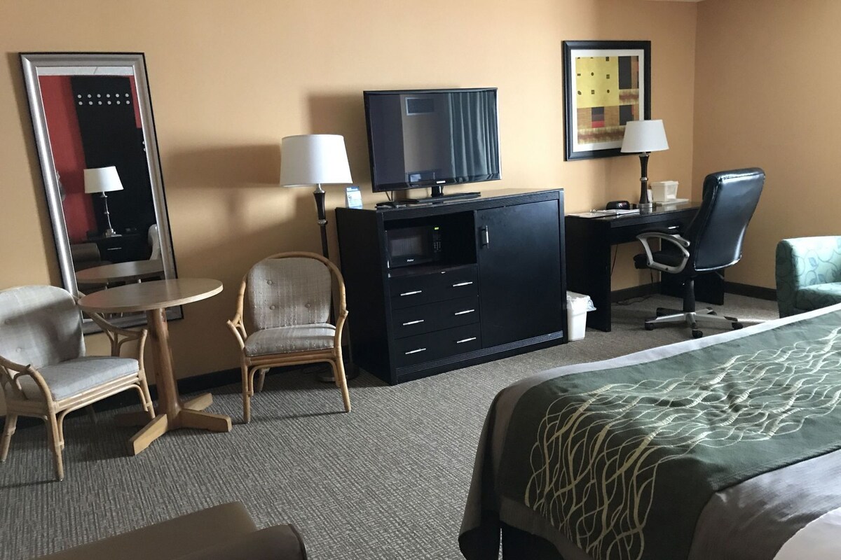 Une chambre d’hôtel comprenant un lit, un bureau avec un ordinateur, une chaise, une télévision et un miroir.
