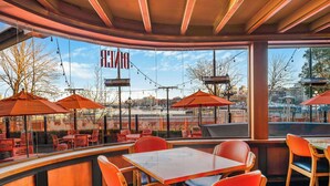 An outdoor seating area with tables and chairs, large windows, and umbrellas. - Days Inn by Wyndham Victoria On The Harbour (Victoria)