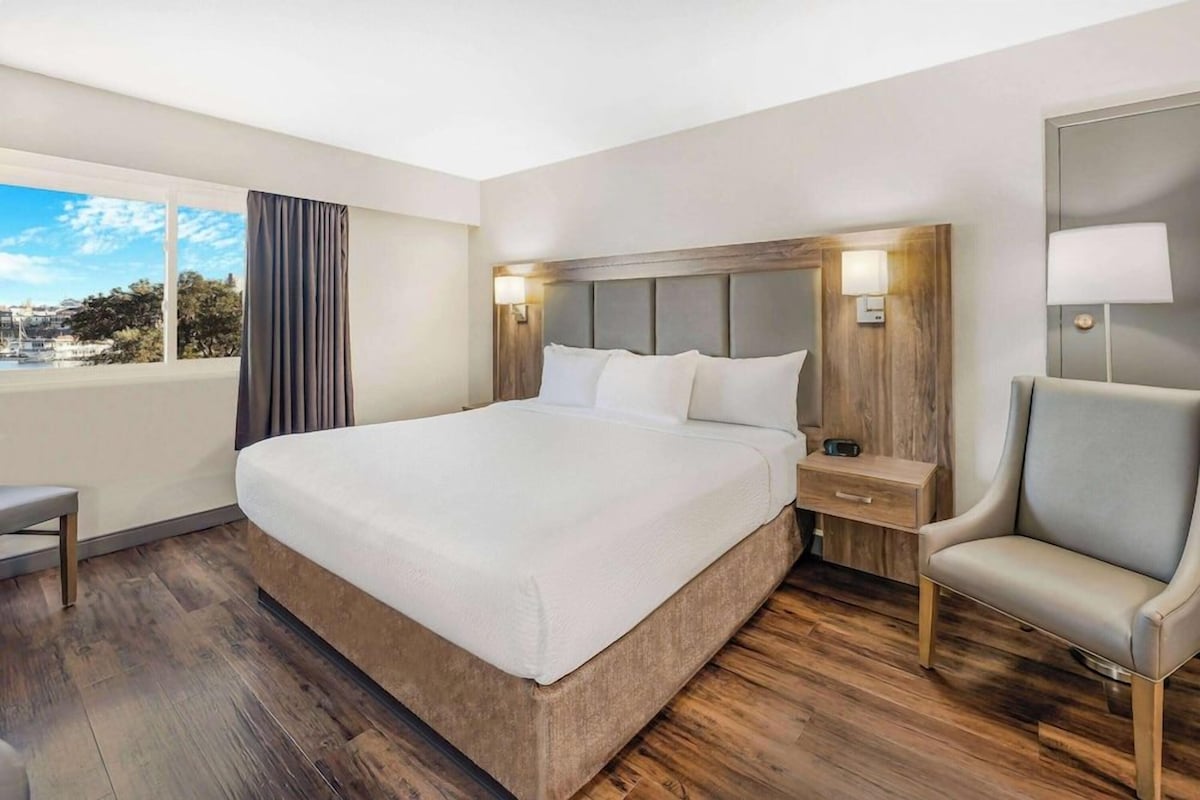 Une chambre d’hôtel avec un grand lit, des tables de chevet, une chaise et une vue sur la ville.