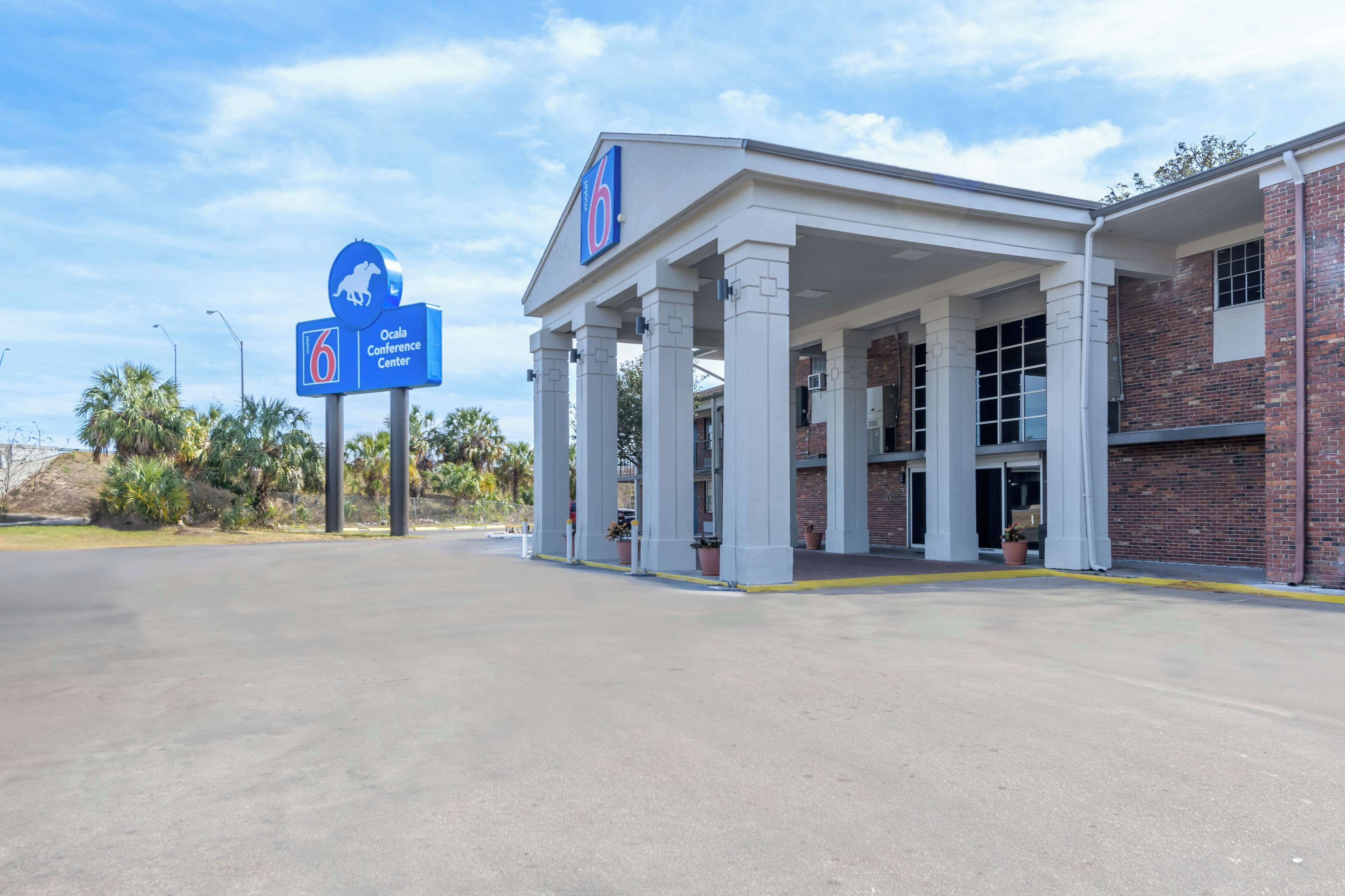A 6-star hotel with a covered outdoor area, a sign indicating the location as the Ocala Conference Center, and a brick building adjacent to it.