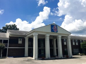 A motel with a prominent '6' sign, a covered entrance with columns, and a brick facade.