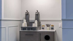A kitchenette with two coffee makers, a small fridge, and various kitchen items.