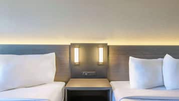 A hotel room with two beds, a nightstand, and a wall-mounted control panel.