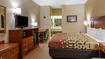 A hotel room with a bed, a desk, a television, and a mirror.