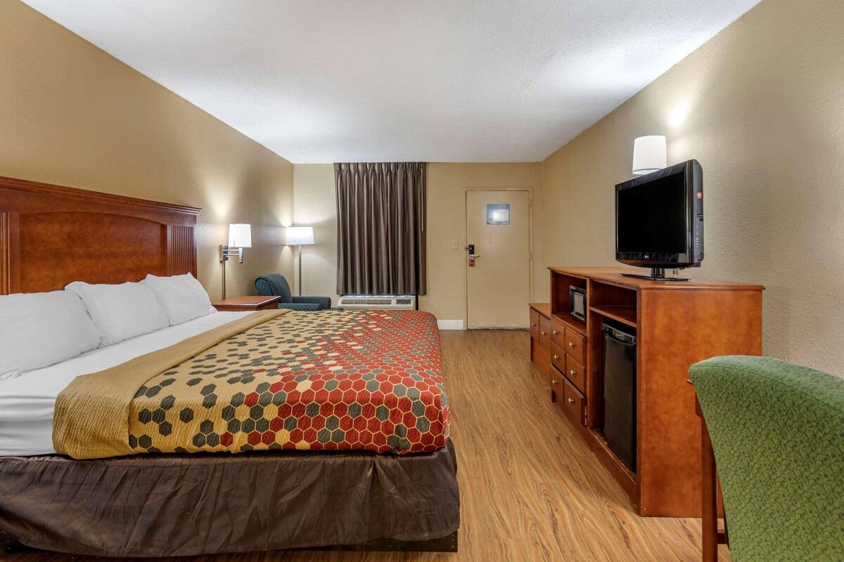 Ein Hotelzimmer mit Bett, Fernseher, Schreibtisch und Stuhl.