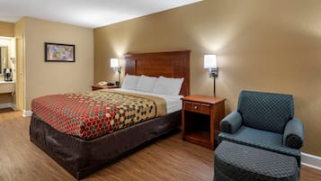 A hotel room with a bed, bedside tables, a chair, and a wall-mounted lamp.