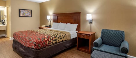A hotel room with a bed, bedside tables, a chair, and a wall-mounted lamp.