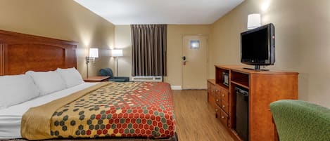Una habitación de hotel con cama, televisión, escritorio y silla.