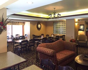 A hotel lobby with a dining area, a sofa, a chandelier, and a clock on the wall. - Econo Lodge Cordele (Cordele)