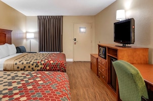 Habitación de hotel con dos camas, televisión, escritorio y una silla.