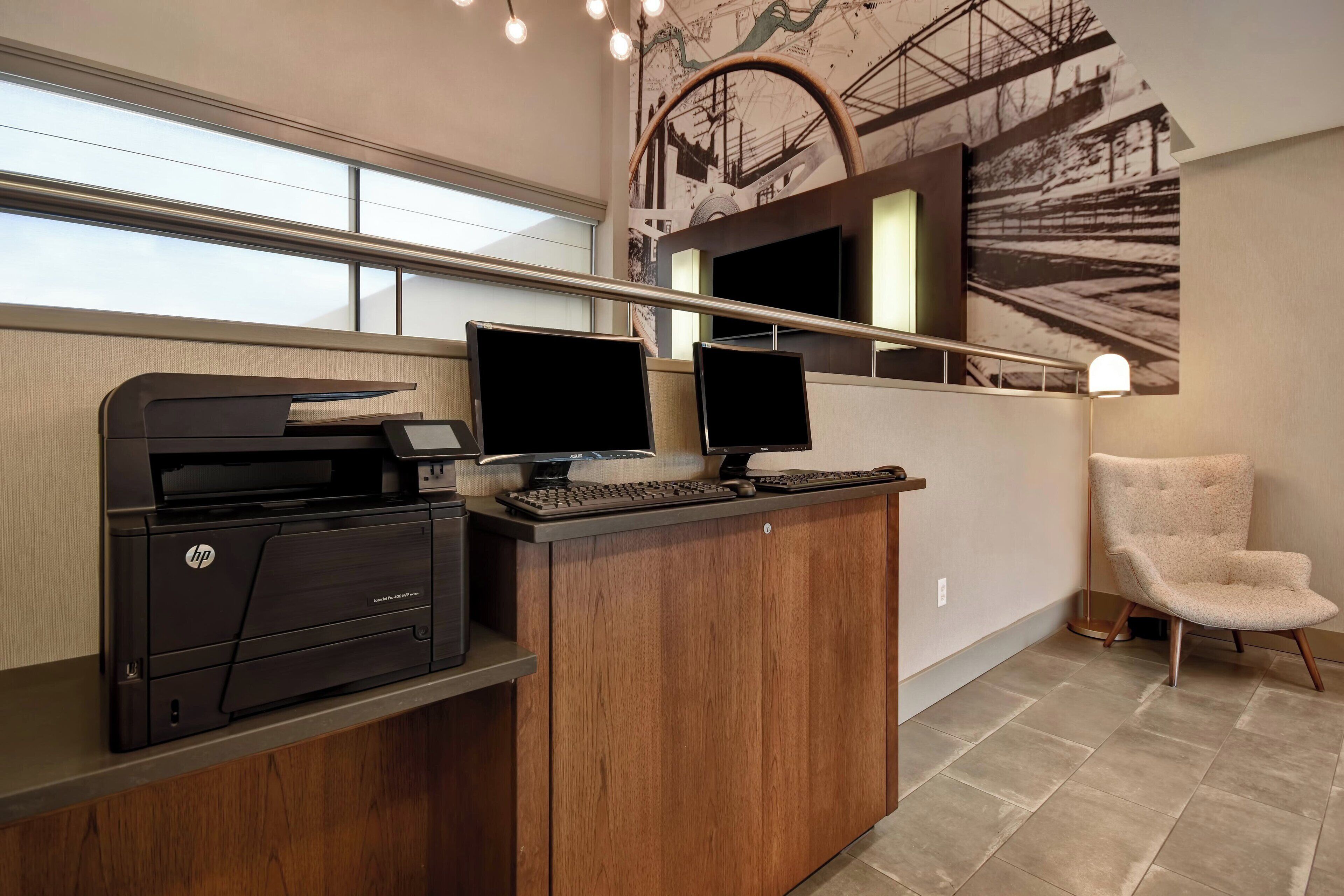 A reception desk with two monitors, a printer, and a chair.