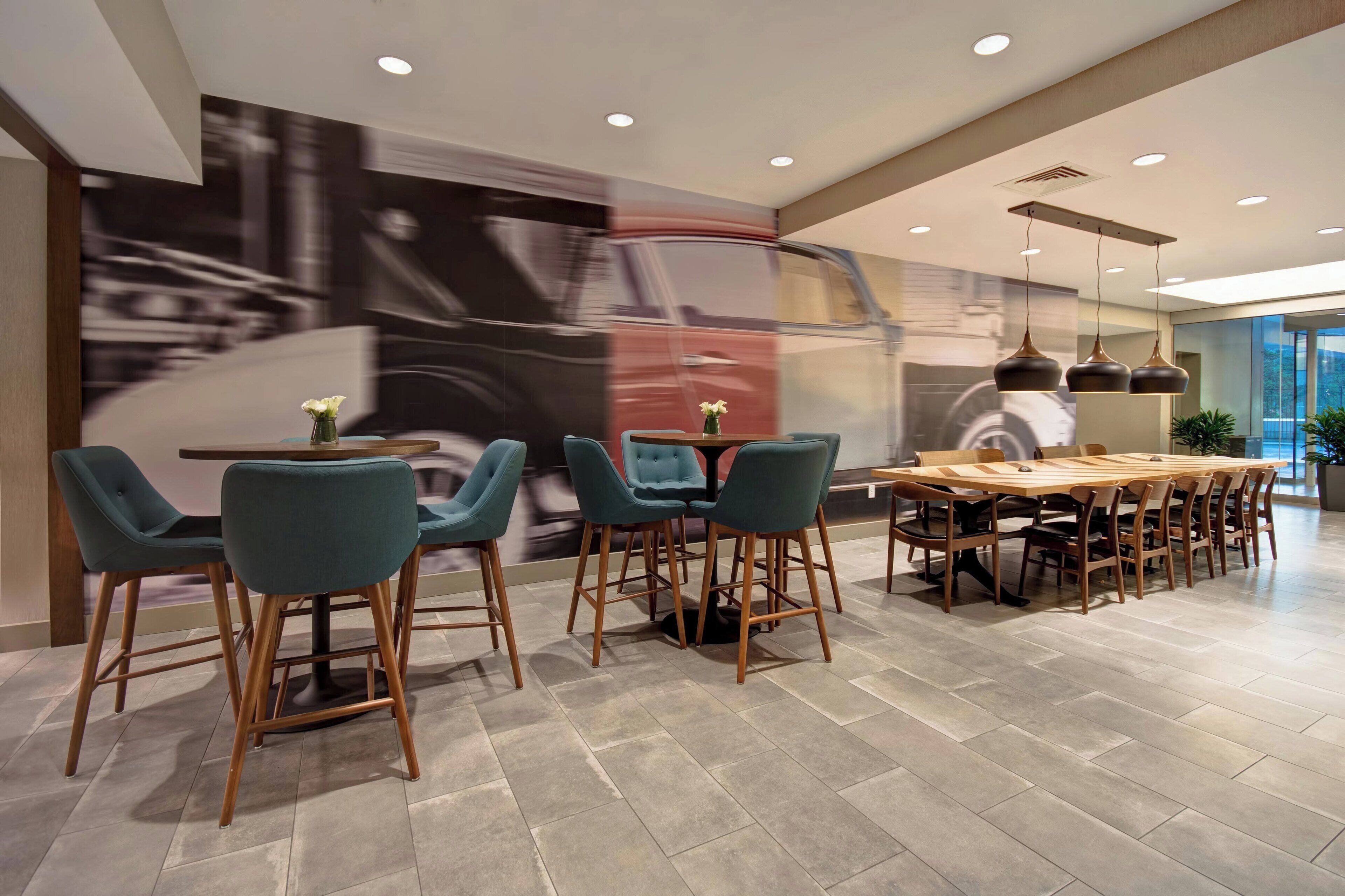 A modern dining area with a large table and chairs, a large abstract painting on the wall, and recessed lighting.