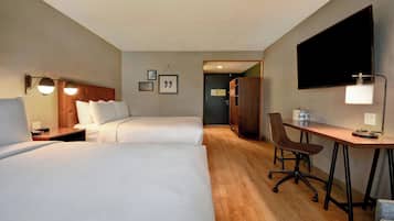 A hotel room with two beds, a desk, a chair, a TV, and a wardrobe.
