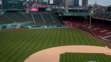 Estadio Fenway Park con un campo de béisbol, asientos verdes y un horizonte urbano al fondo.