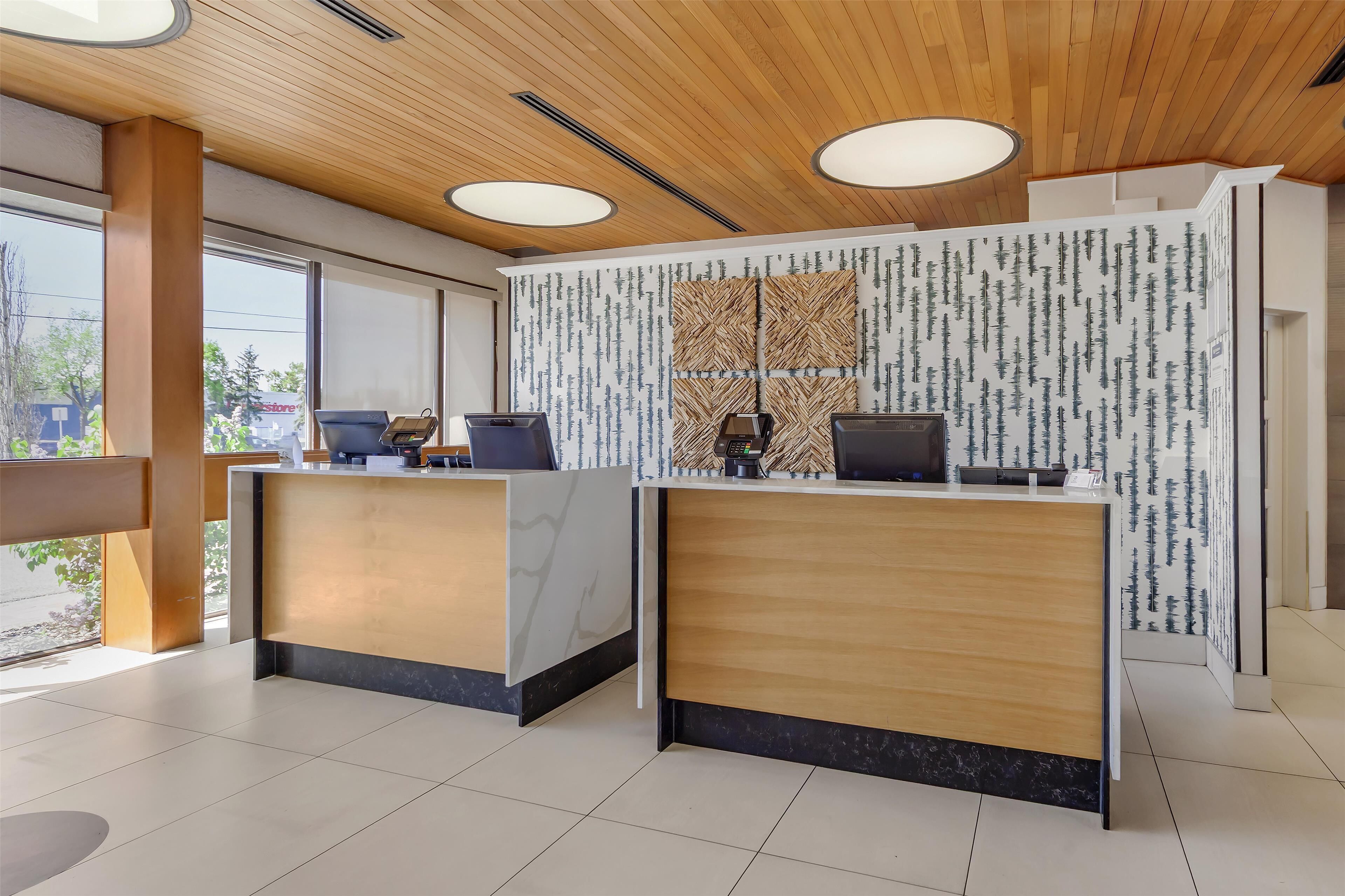 A modern reception area with two reception desks, wooden ceiling, and large windows.