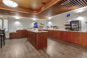 Una cocina moderna con armarios de madera, una isla central y electrodomésticos integrados, incluyendo una cafetera y un refrigerador.