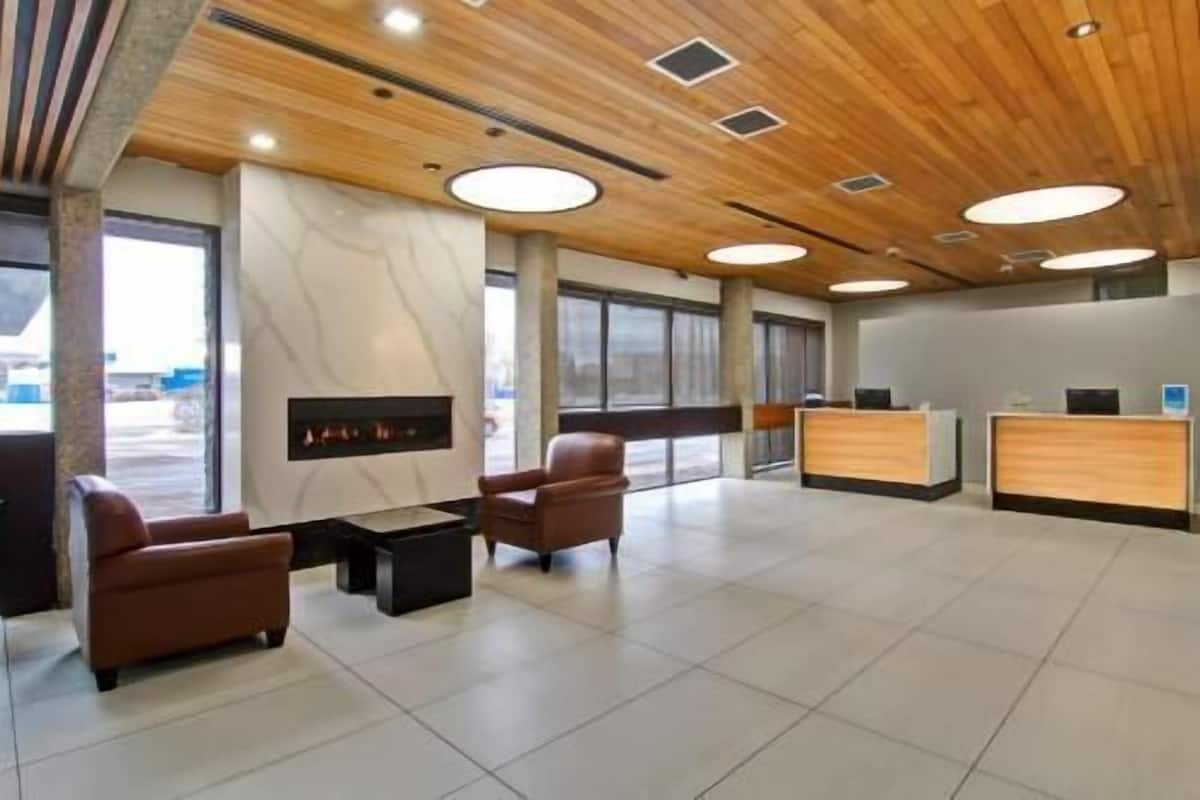 A spacious lobby with a wooden ceiling, a fireplace, leather chairs, and a reception desk.