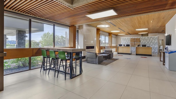 A spacious, modern lobby with a wooden ceiling, large windows, a reception desk, and seating areas. - Best Western Cedar Park Inn (Edmonton)