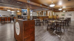 A spacious restaurant with wooden ceilings and a bar area. Tables and chairs are arranged for dining. - Best Western Cedar Park Inn (Edmonton)