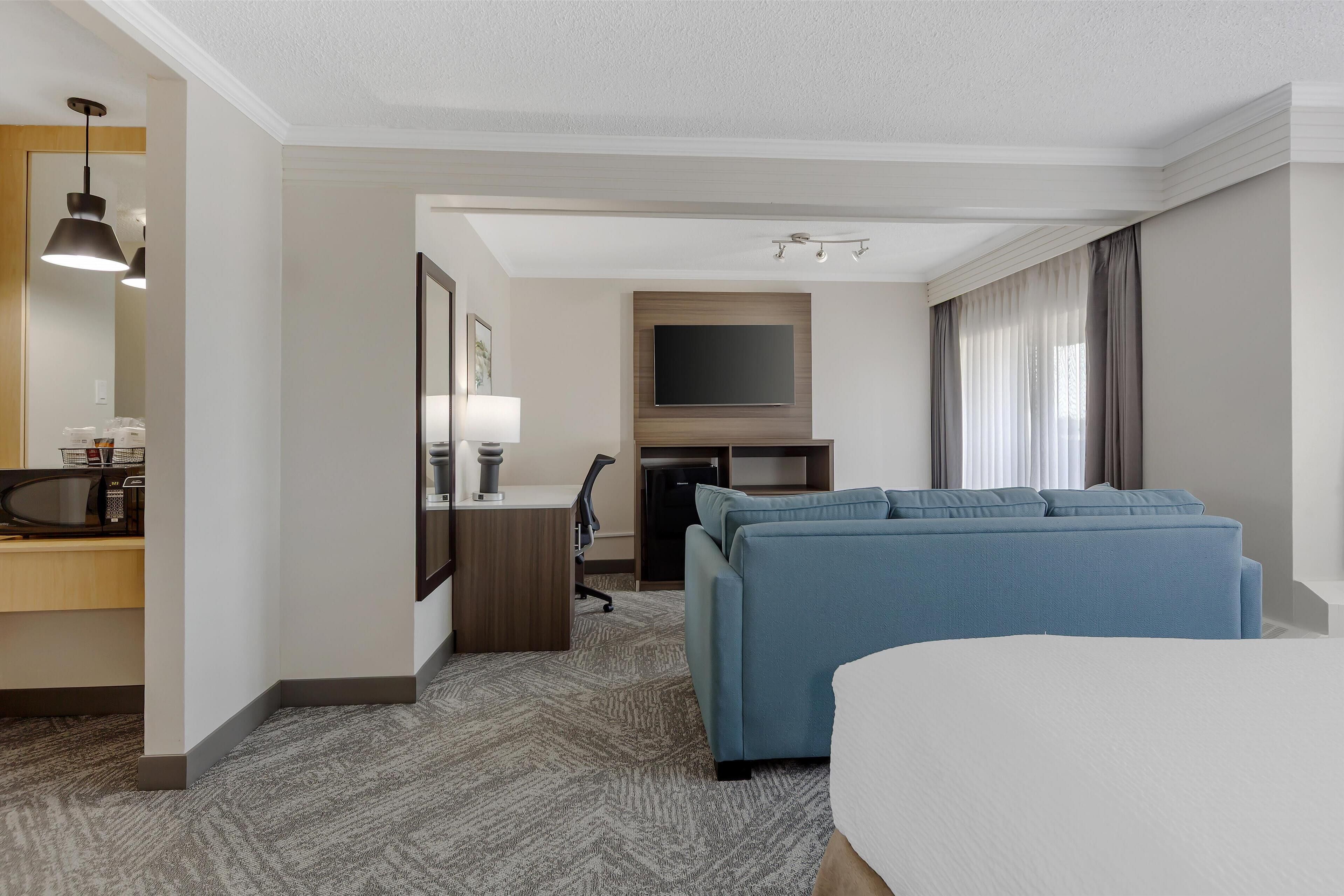 Una habitación de hotel con cama, escritorio con computadora, televisor y sofá.
