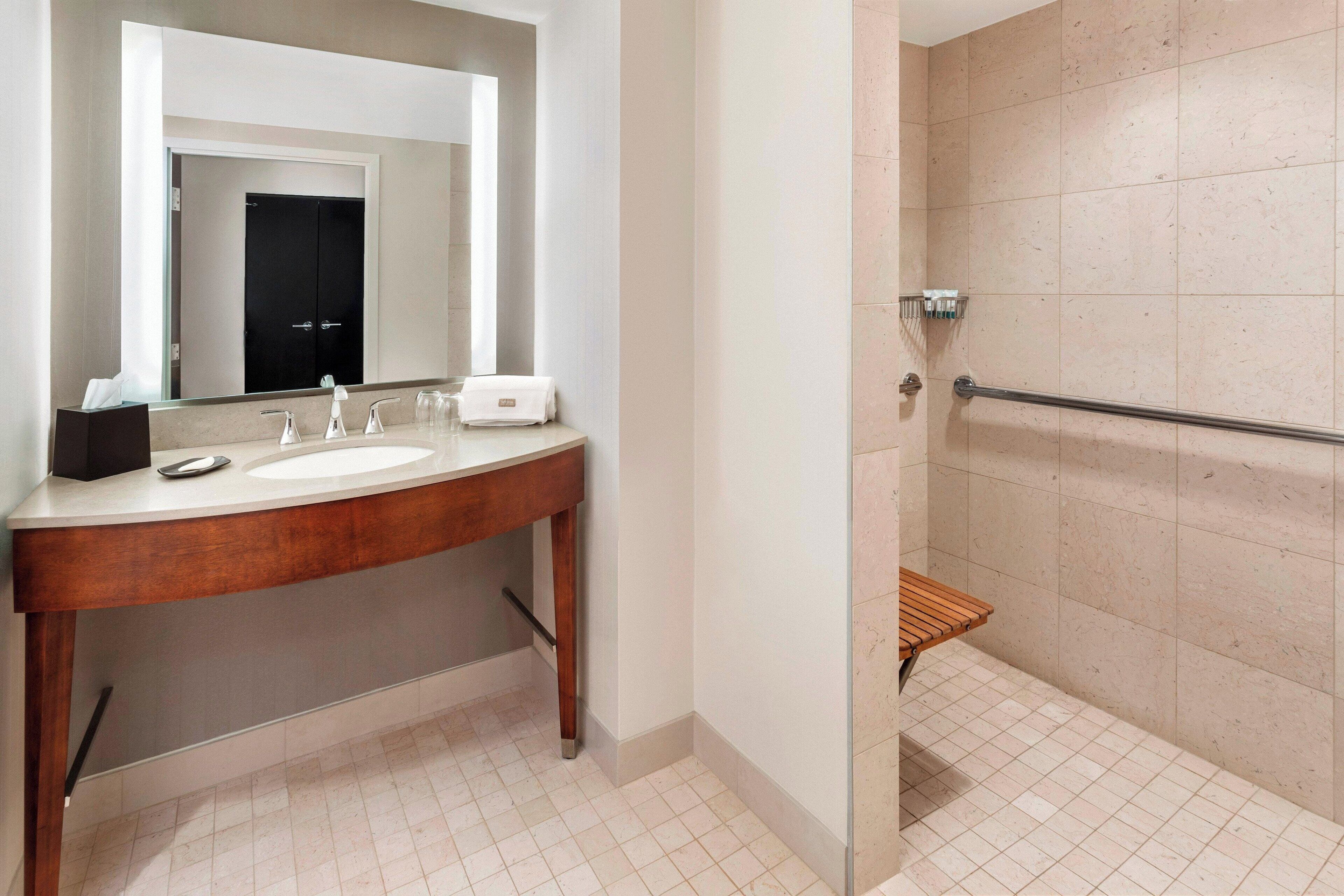 A bathroom with a wooden vanity, a large mirror, and a glass shower enclosure.