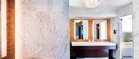 A modern bathroom with a marble wall, a large sink, and a bowl on the counter.