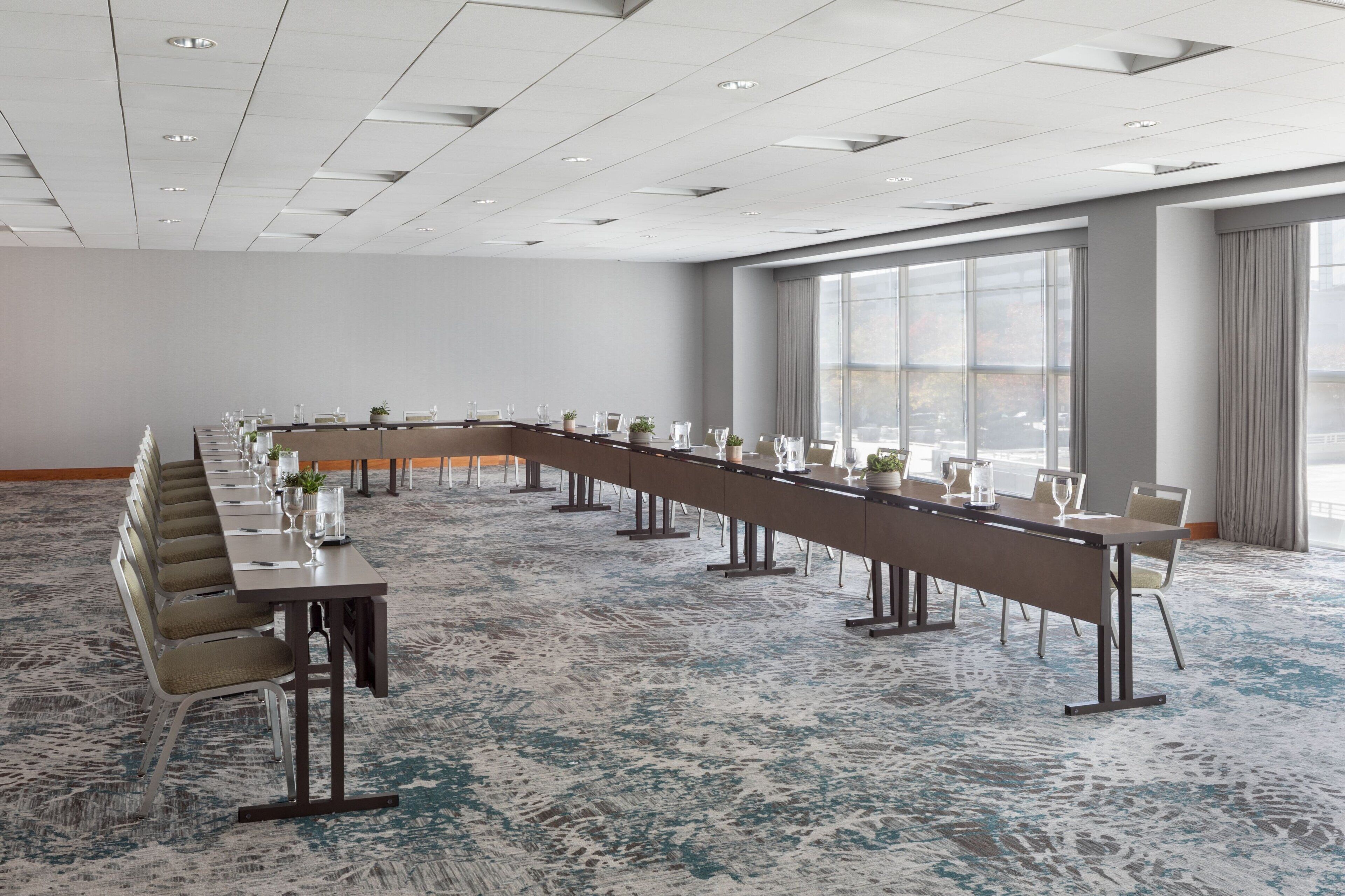 A conference room with a long table, chairs, and a carpeted floor.