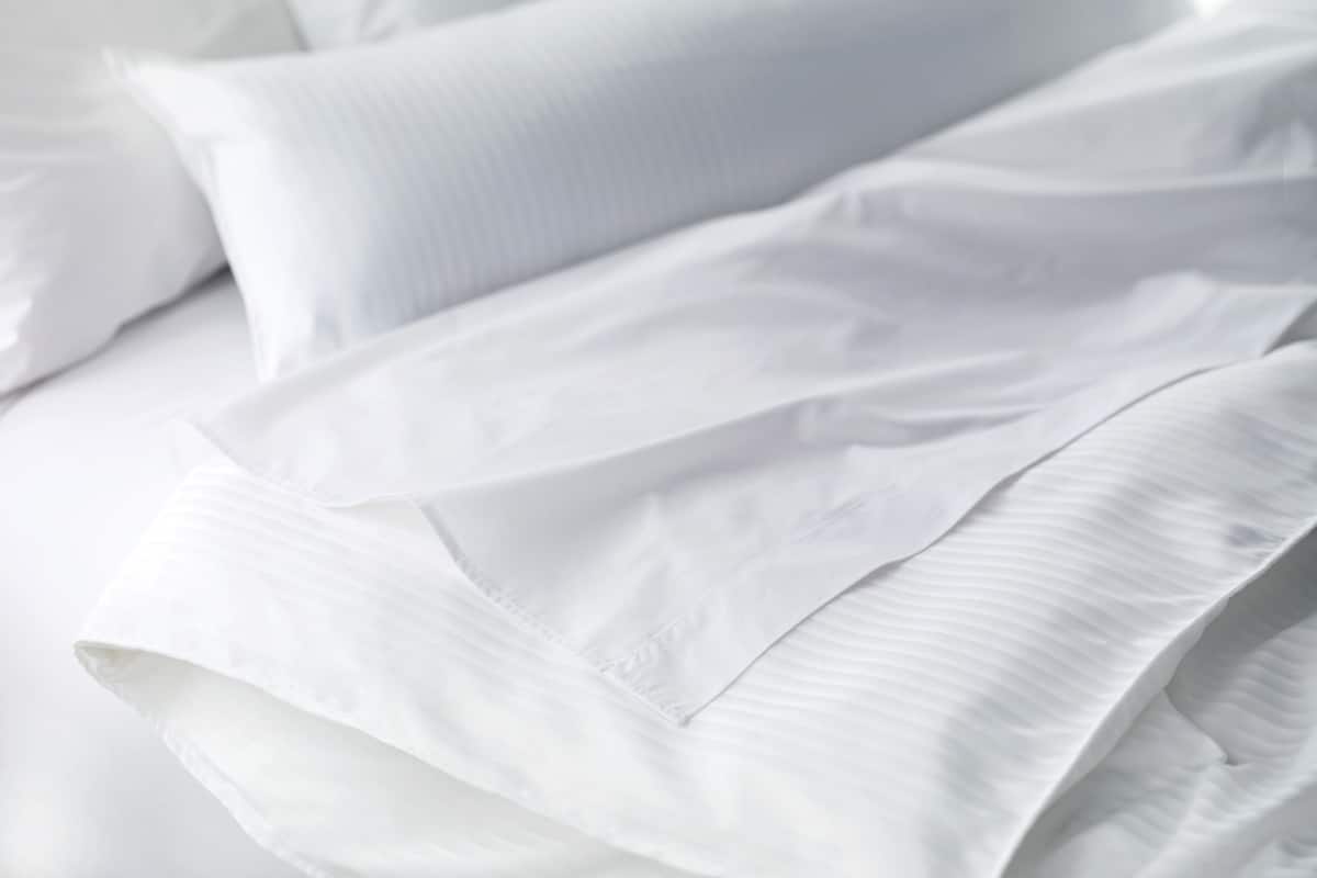 Una cama bien hecha con sábanas y almohadas blancas.