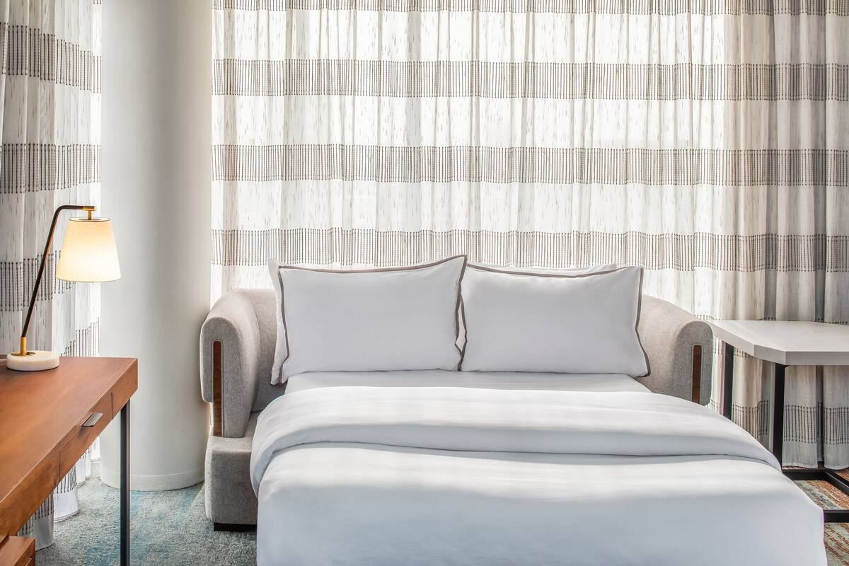 Habitación de hotel ordenada con una cama, un escritorio y una silla.