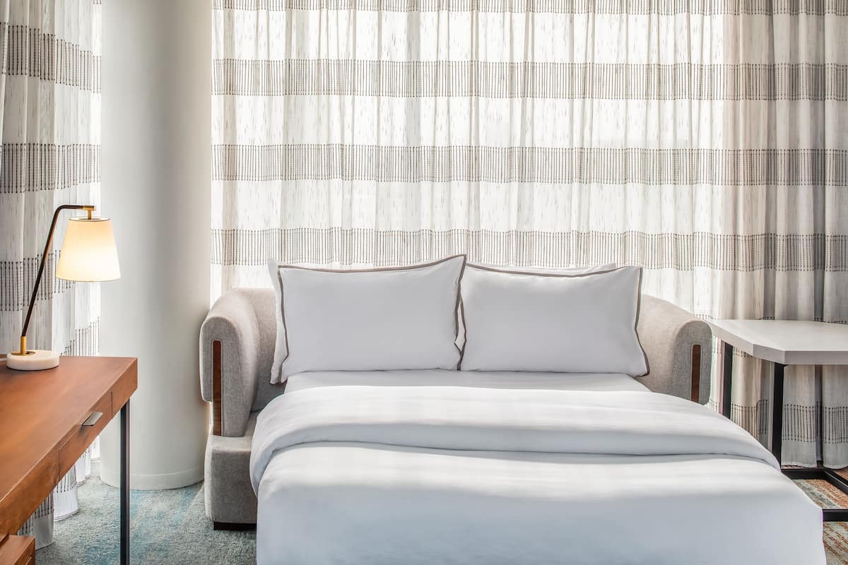 Habitación de hotel ordenada con una cama, un escritorio y una silla.