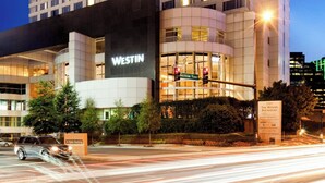 A Westin hotel with a prominent sign, multiple floors, and a parking area.