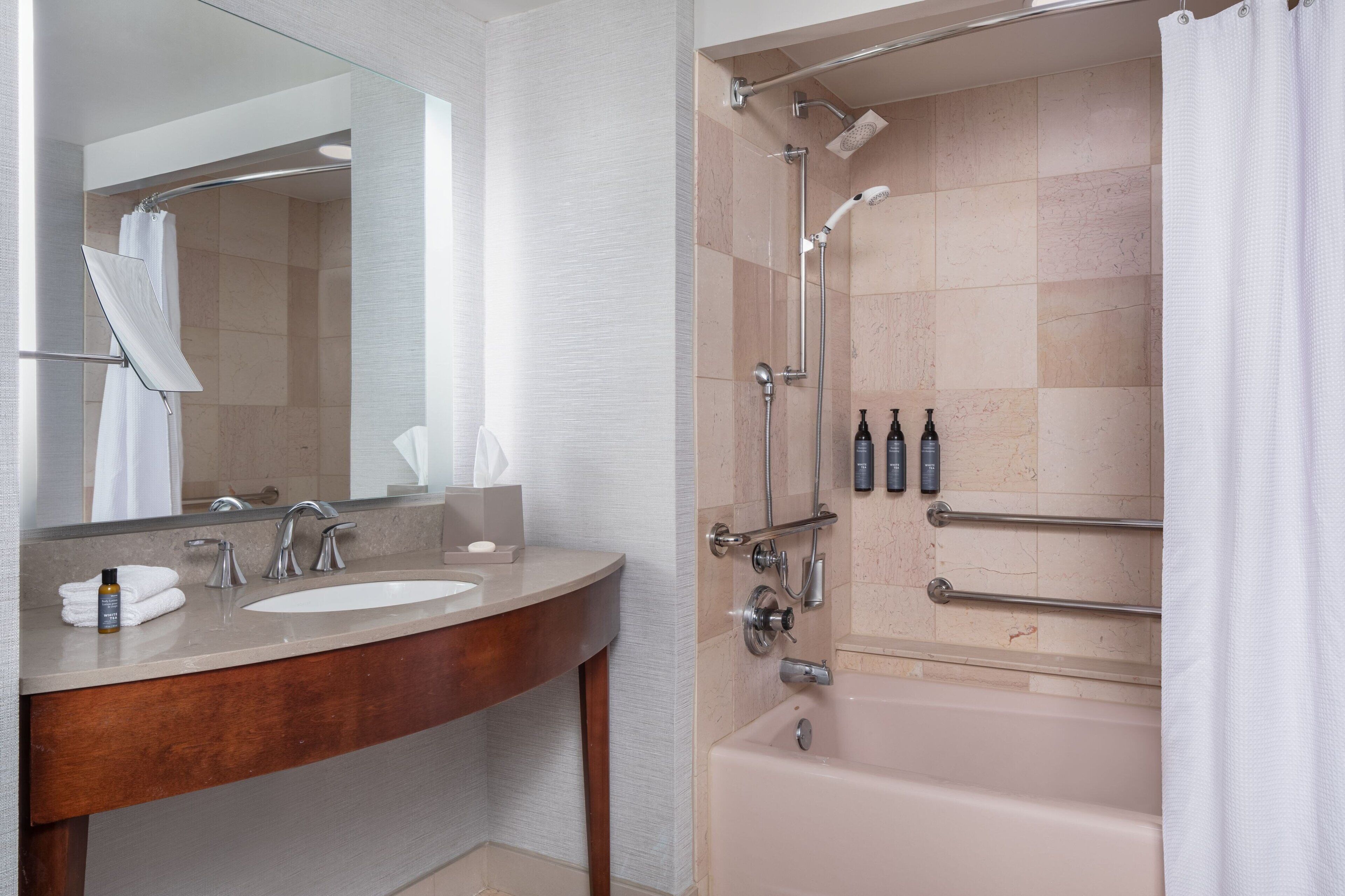 Un baño con tocador de madera, un espejo grande, una bañera y zona de ducha.