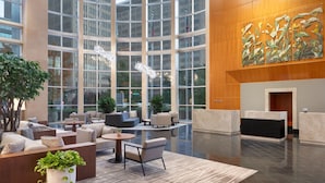 A spacious lobby with a modern design, featuring a reception desk, seating areas, and large windows offering views of the cityscape.
