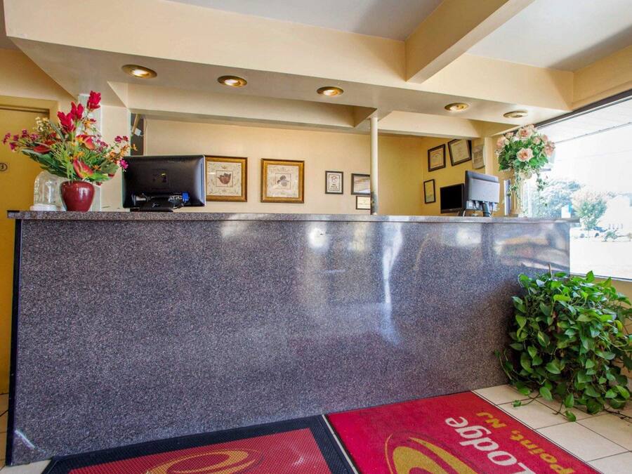 A reception area with a granite counter, framed certificates on the wall, and a doormat with the hotel's name.
