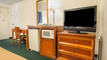 Una habitación de hotel con una cama, un escritorio con microondas, televisor y cómoda.
