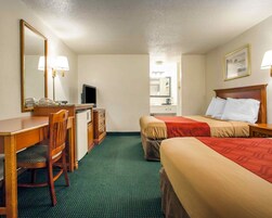 Una habitación de hotel con escritorio, silla, dos camas, televisor y espejo.
