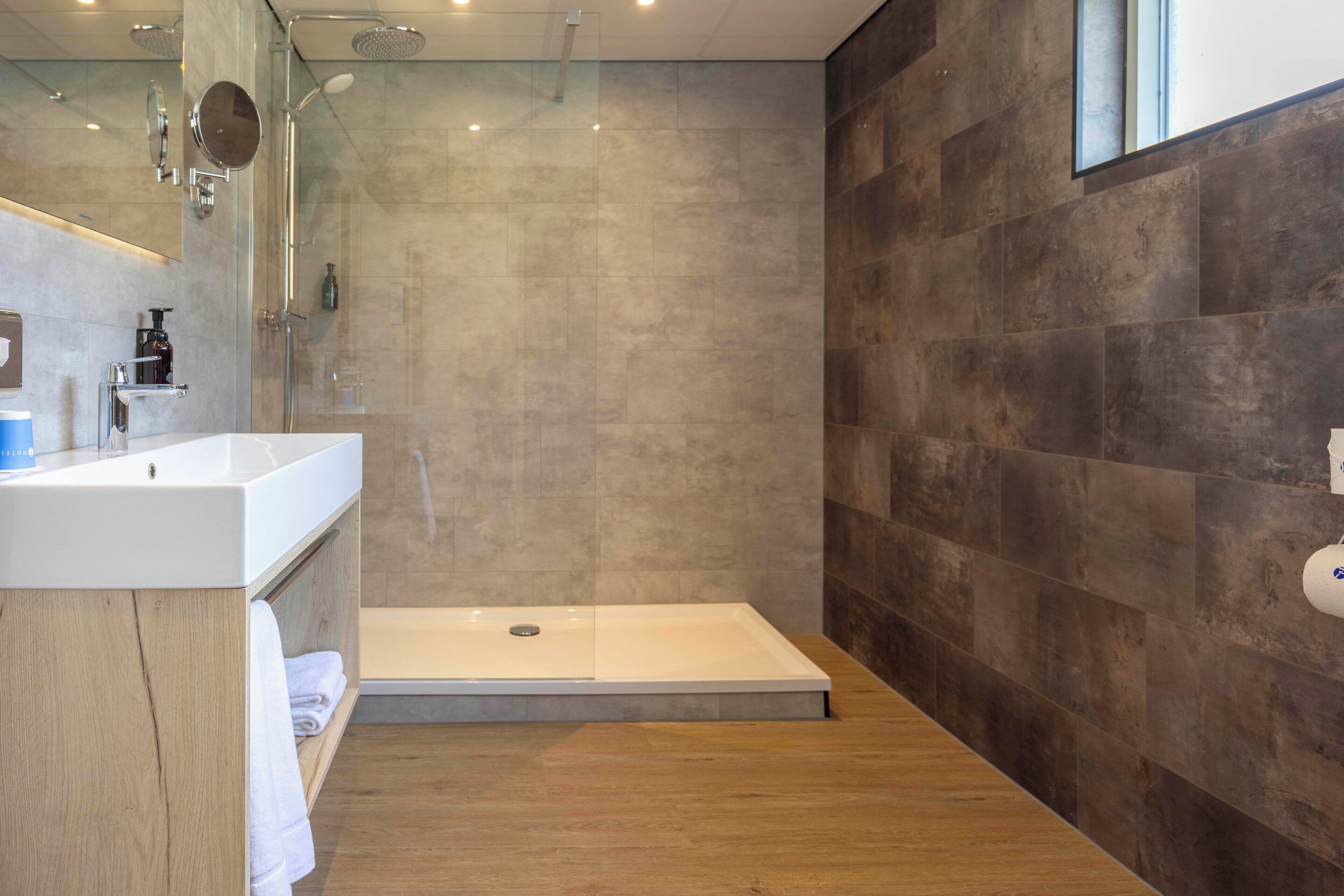 A modern bathroom with a shower, a sink, and a mirror.