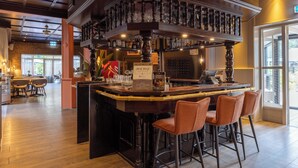 A bar area with a wooden bar, stools, and a menu sign. - Fletcher Hotel - Restaurant Victoria - Hoenderloo (Hoenderloo)