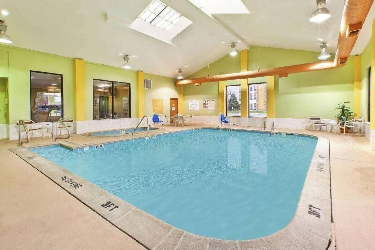 Una piscina interior con agua cristalina, rodeada de paredes amarillas y un suelo de baldosas.