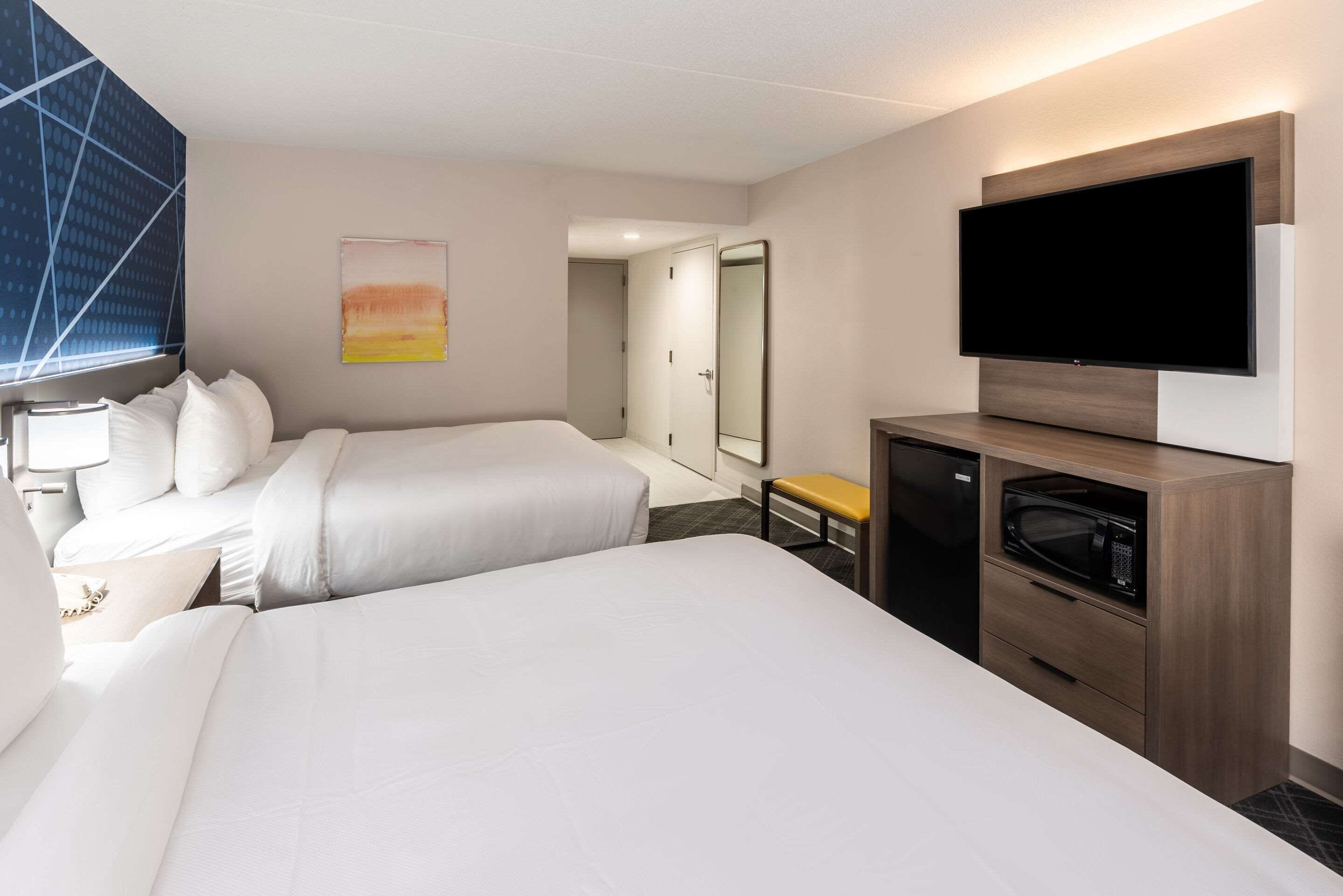 A hotel room with two beds, a TV, a microwave, and a small table.