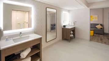 Un baño moderno con un espejo grande, un lavabo y una cómoda. Hay un perchero y una repisa con toallas.